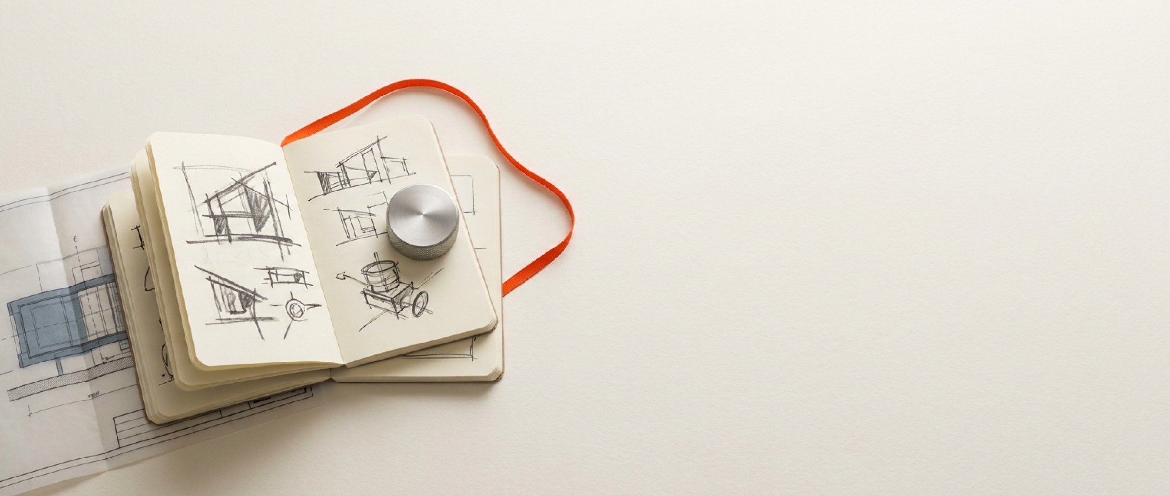 Field notebooks with engineering sketches, a machined dial and an orange bookmark ribbon