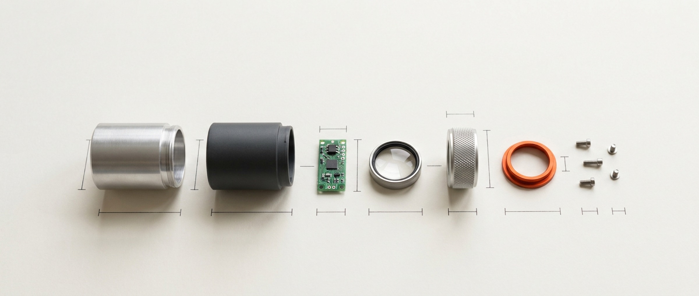 Exploded view of a precision instrument's components laid out in a row with one orange part