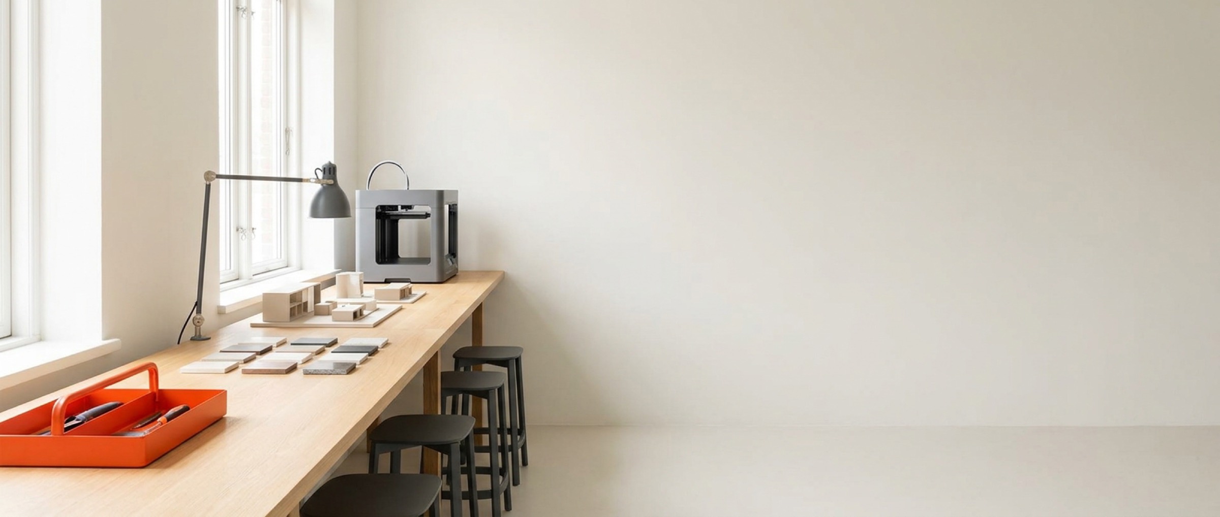 Calm studio workbench with prototypes, material samples and a 3D printer in natural light